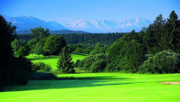 Golfanlage mit Bäumen und Blick zu den Alpen