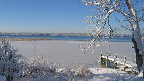 Winteransicht von gefrorenem Starnberger See mit verschneitem Steg