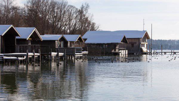 Boat houses with snowy roofs in front of lake