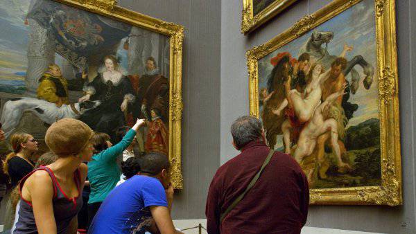Mehrere Menschen betrachten barocke Gemälde in goldenen Rahmen