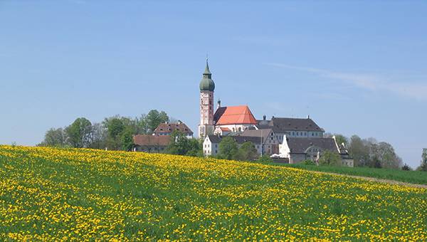 Kloster Andechs auf Anhöhe vor grüner Wiese mit gelben Blumen