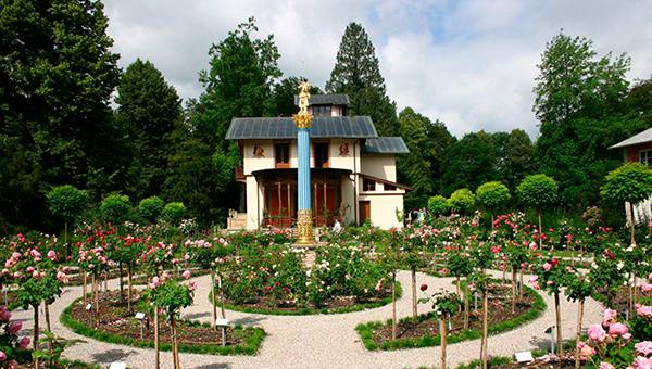 Angelegter Garten mit Bäumen und Beeten vor Villa