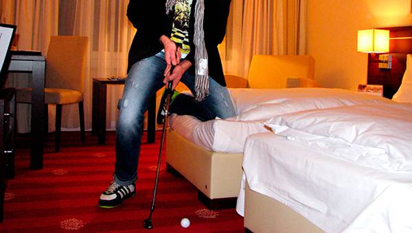 Man holding golf club in hotel room