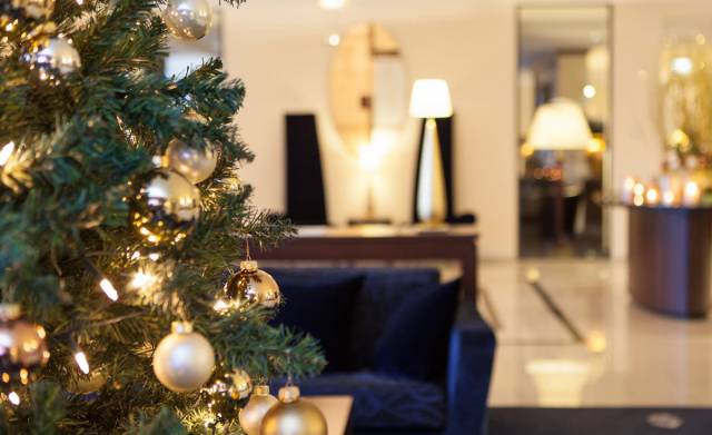 Picture of lobby in the background, gold decorated Christmas tree in focus