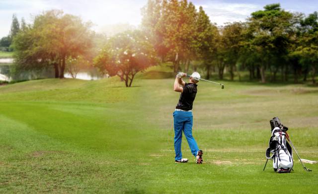 Golfer macht Abschlag auf einem Golfplatz mit See