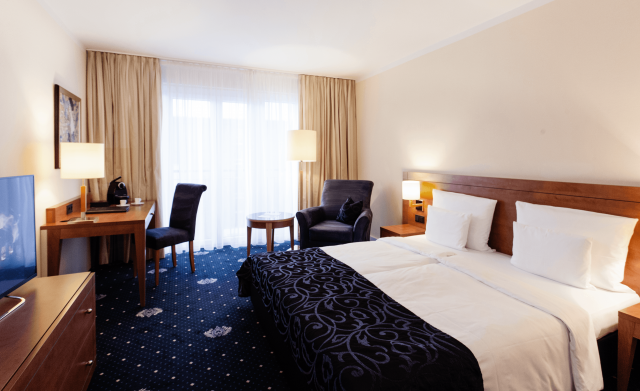 Zimmeransicht Doppelzimmer mit King-Size-Bett, Flatscreen-TV und großem Fenster mit Schreibtisch
