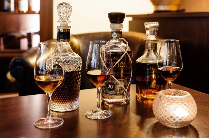 Three rums in glasses with corresponding bottle in the background